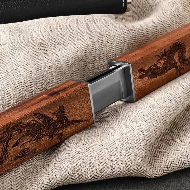 Vue rapprochée du mécanisme d'emboîtement des manches en bois gravés dragon d'un couteau japonais Tanto à double lame sur un tissu beige.