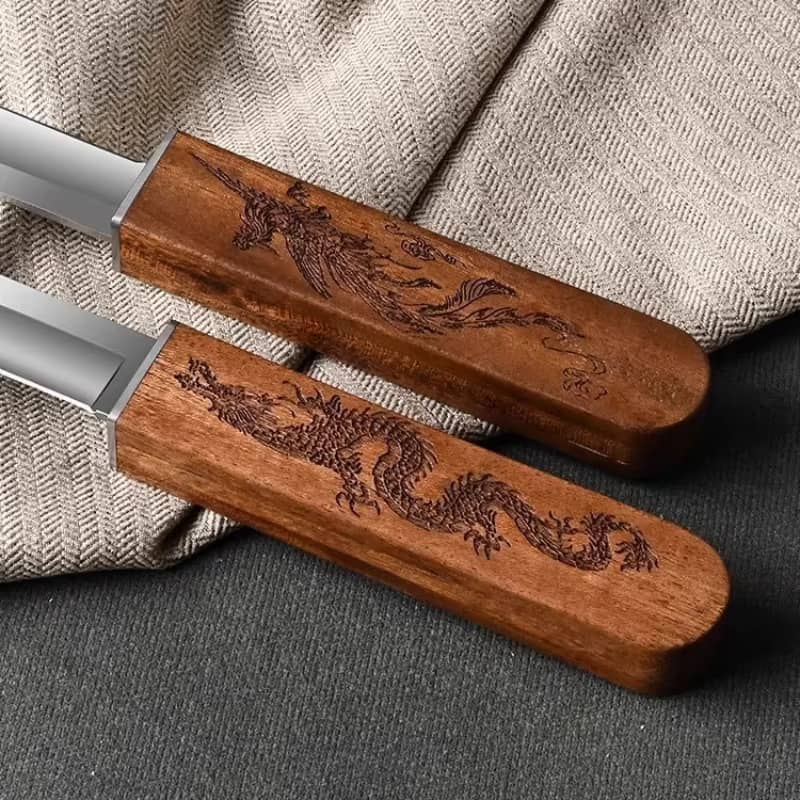 Gros plan sur les gravures précises d'un dragon et d'un phénix sur les manches en bois de deux couteaux Tanto japonais, placés sur un tissu beige.