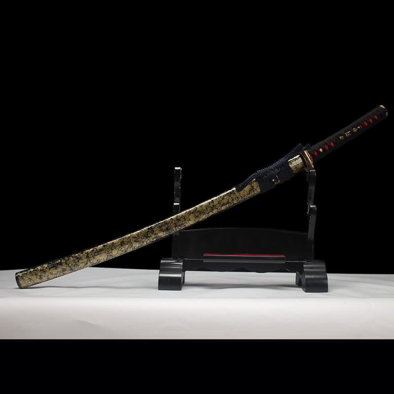 Katana japonais “Okinawa” en acier T10 trempé à l’argile, présenté avec son fourreau doré sur support.