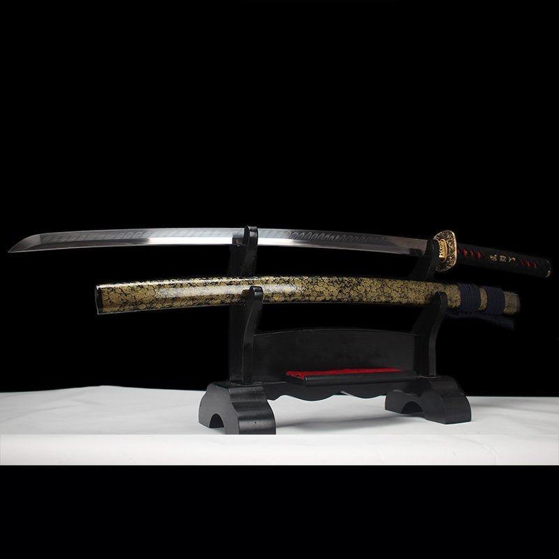 Katana japonais “Okinawa” en acier T10 avec hamon authentique, lame dégainée et fourreau doré sur support.