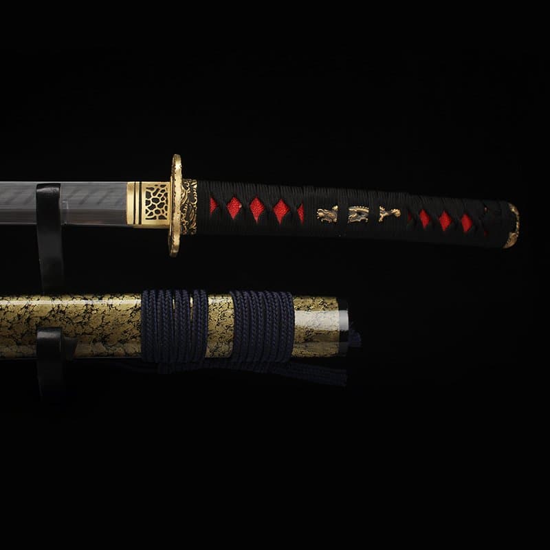 Détail de la poignée noire avec tressage rouge et ornements dorés du katana japonais “Okinawa” en acier T10.