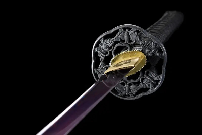 Vue rapprochée de la garde tsuba noire du katana japonais Tomoe Gozen avec lame pourpre en acier carbone plié