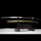 Katana japonais “Okinawa” en acier T10 avec hamon authentique, lame dégainée et fourreau doré sur support.