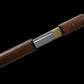 Gros plan sur le manche du katana japonais Shirasaya en bois de rose avec finitions artisanales.