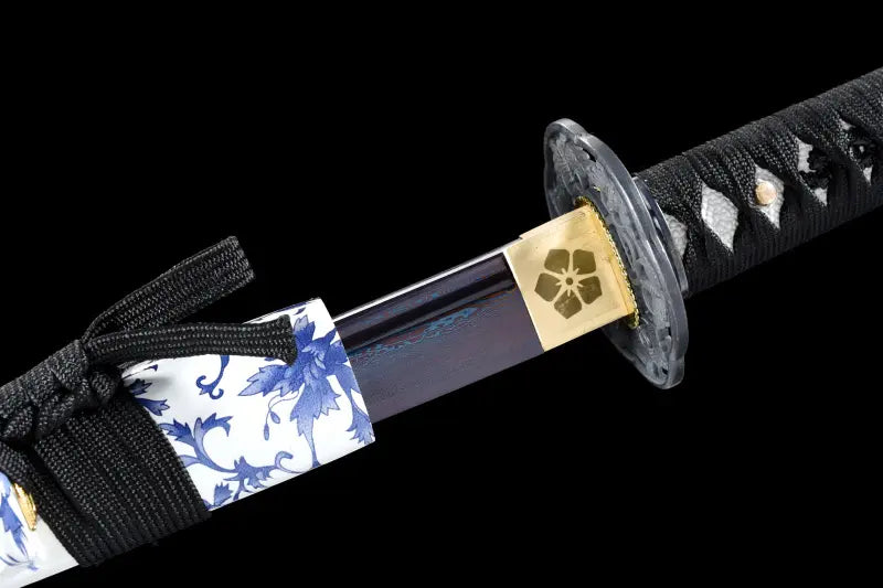 Sortie de lame du katana japonais Tomoe Gozen en acier carbone plié, saya blanc fleuri et habaki doré.